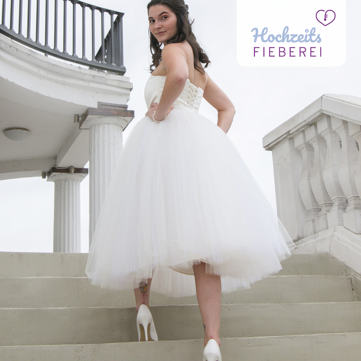 Brautmodel auf Treppe Rückenansicht kurzes Kleid