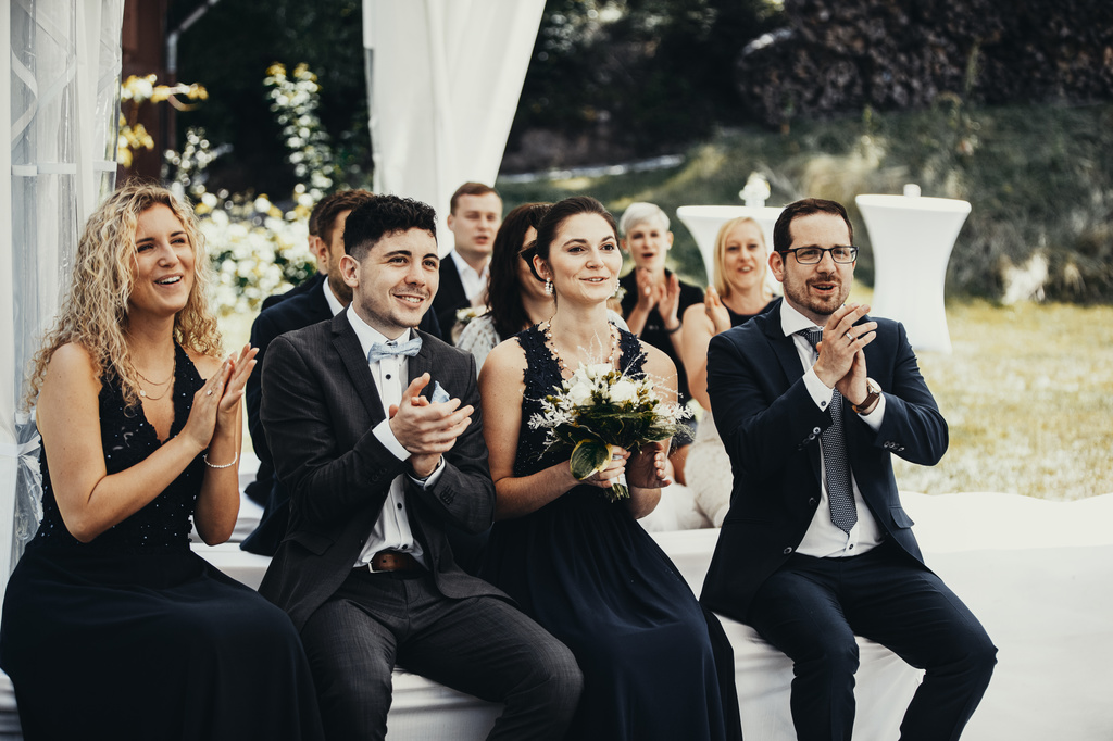 Die Hochzeitsgäste applaudieren.